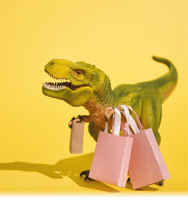 Studio shot of small plastic tyrannosaurus with small paper shopping bags isolated on yellow background.