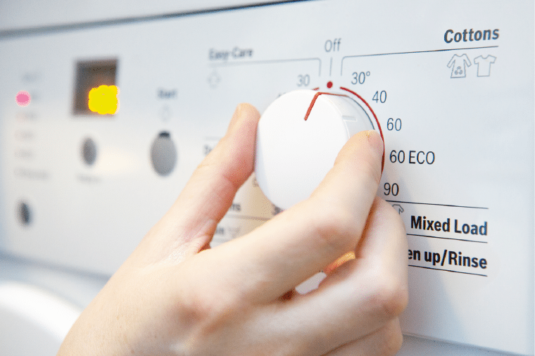 Woman Selecting Cooler Temperature On Washing Machine To Save Energy